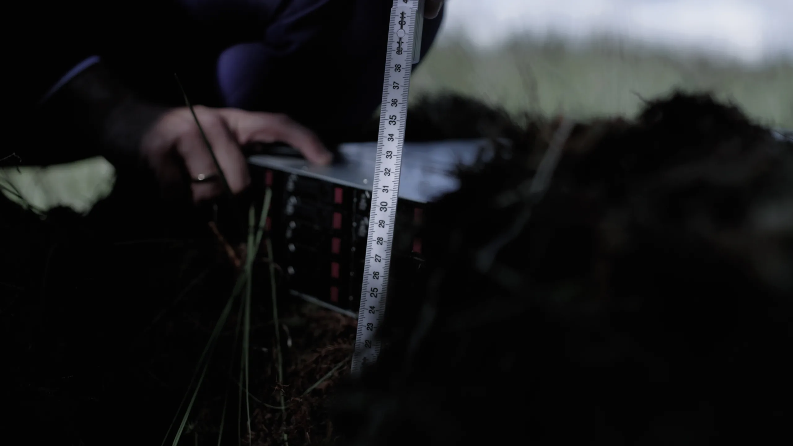 Cinematisk stillbillede fra en professionel videoproduktion for et datacenter, der viser it-hardware blive gravet ned i mørk jord. Billedet er et eksempel på kreativ visuel storytelling og produktion af brandingfilm til it-branchen, hvor humoristiske referencer og unikke vinkler kombineres for at skabe engagerende erhvervsvideo.