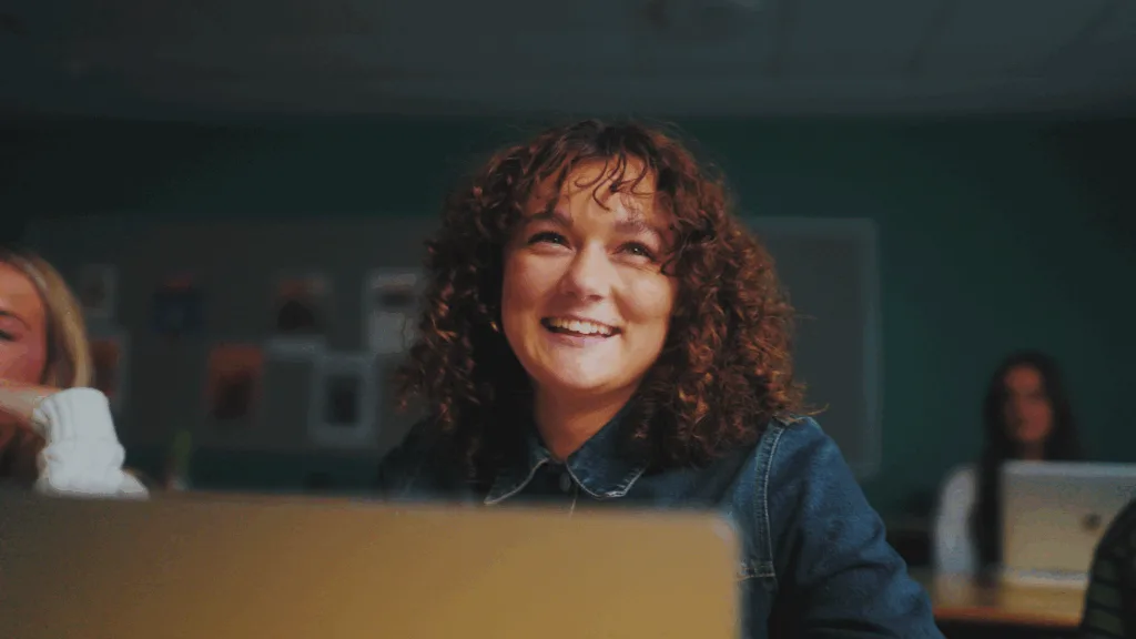 Cinematisk tæt-på klip fra en professionel brandingfilm til et gymnasie, der fanger en autentisk og glad elev i et studiemiljø. Eksempel på videoproduktion til uddannelsesinstitutioner med fokus på visuel storytelling, høj billedkvalitet og engagerende content.